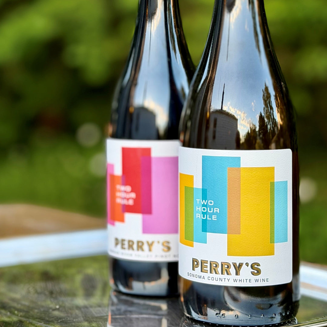 Two bottles of Perry's wine on a table with a blurred green background